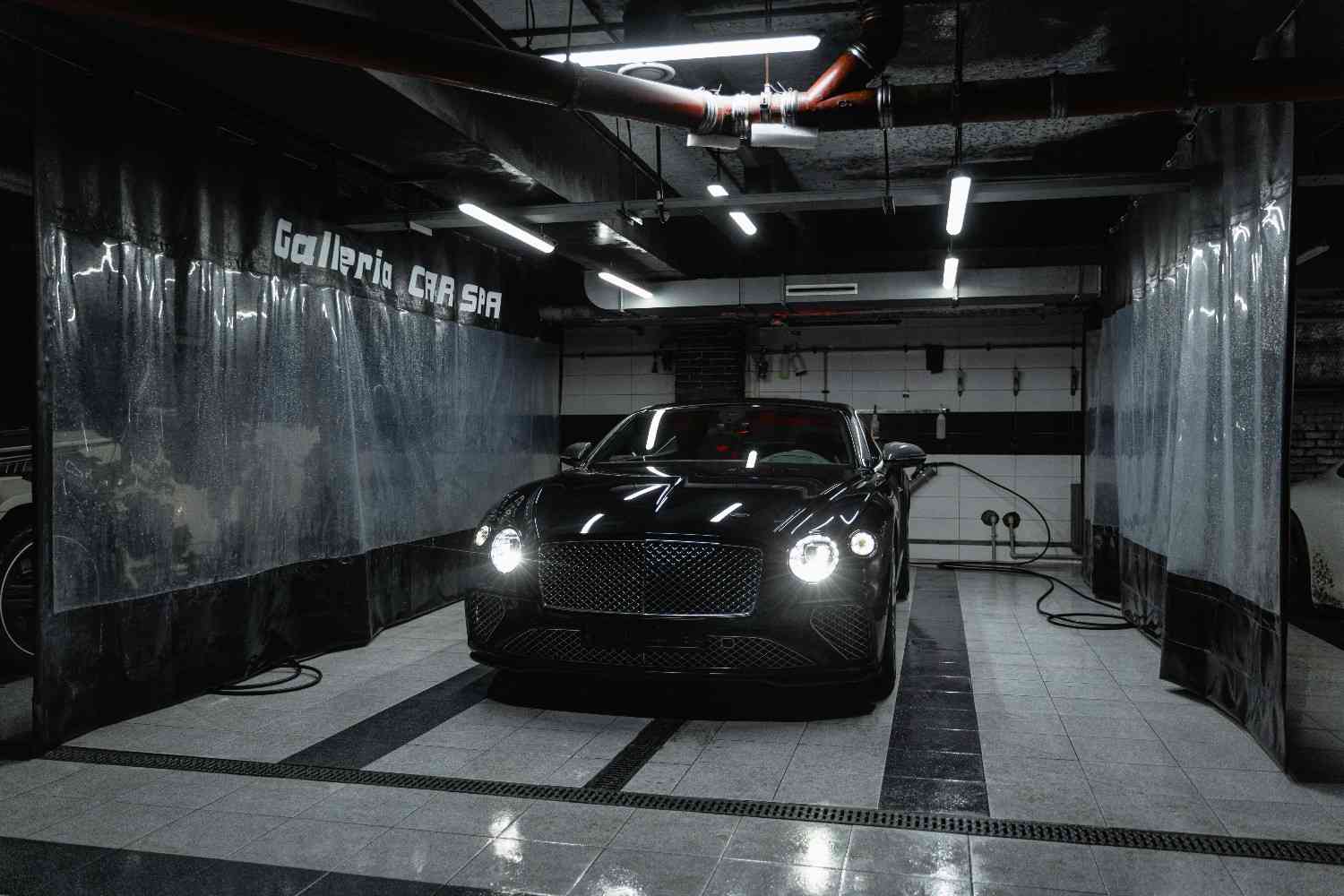 A sleek dark modern car parked in a high-tech garage with soft blue lighting reflecting off the metallic paint